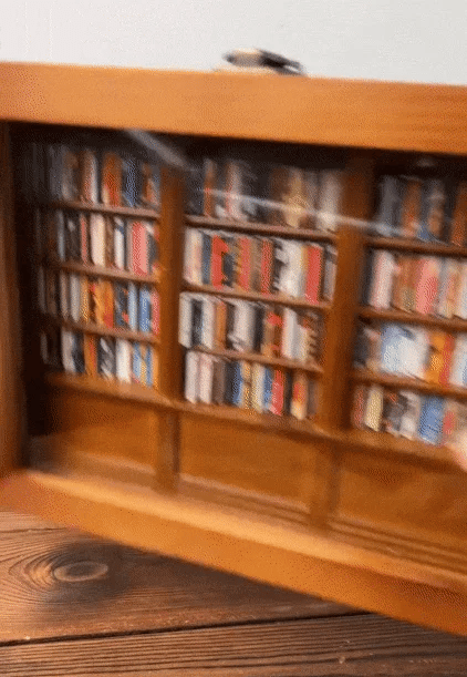 Brown wooden bookcase cabinet with glass doors, shelves of books inside