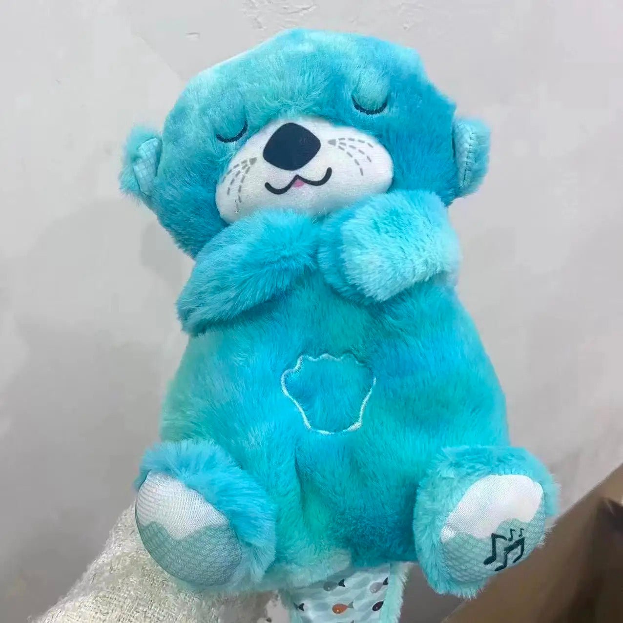 Blue plush bear sleep aid with embroidered face, closed eyes, stitched heart emblem