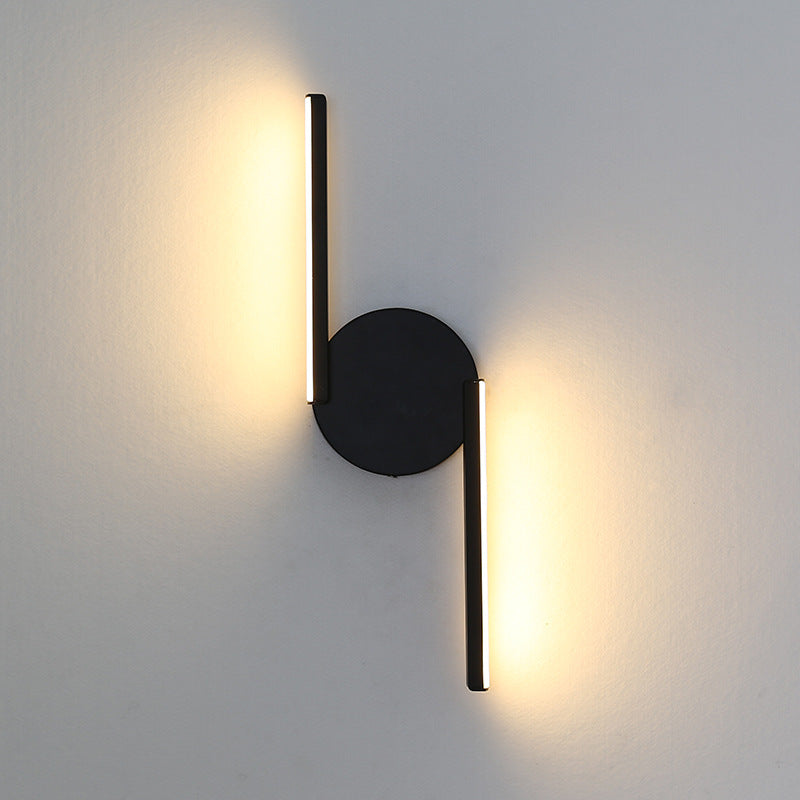 Black LED wall lamp with round backplate and vertical light bar, warm glow.