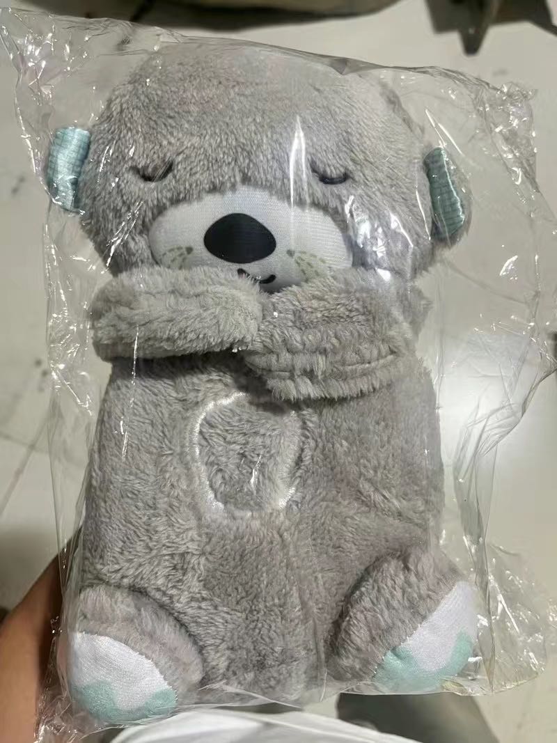 Gray plush otter baby sound machine, closed eyes and teal paw pads