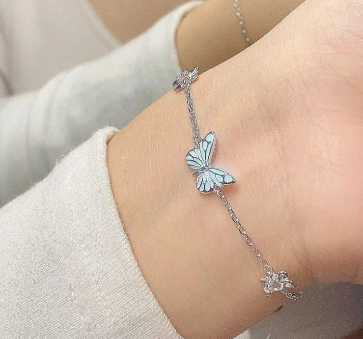 Silver chain bracelet with blue butterfly charm and dangling detail