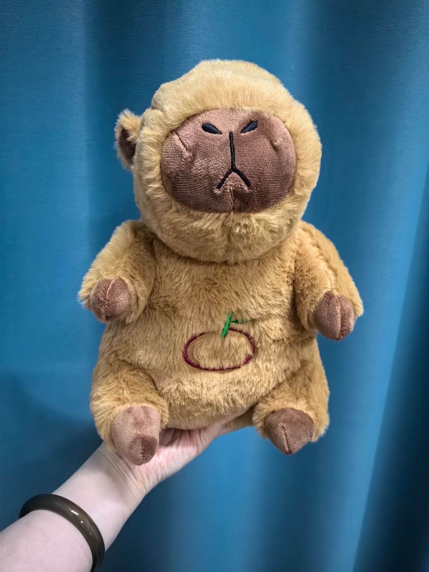 Tan plush bear sound machine with closed eyes and stitched mouth, glowing belly panel