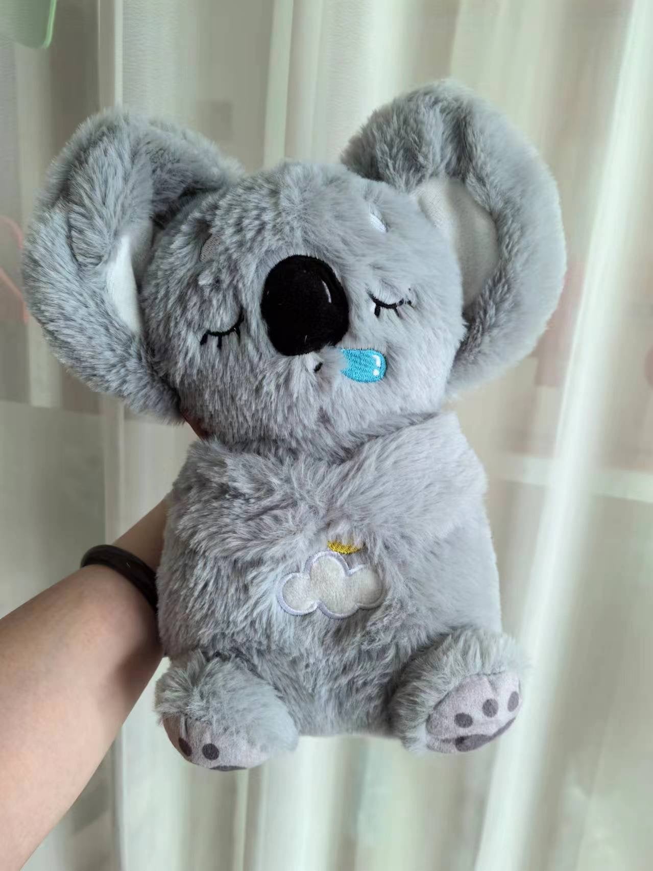 Gray koala plush baby sound machine, stitched smile and cloud patch on chest.