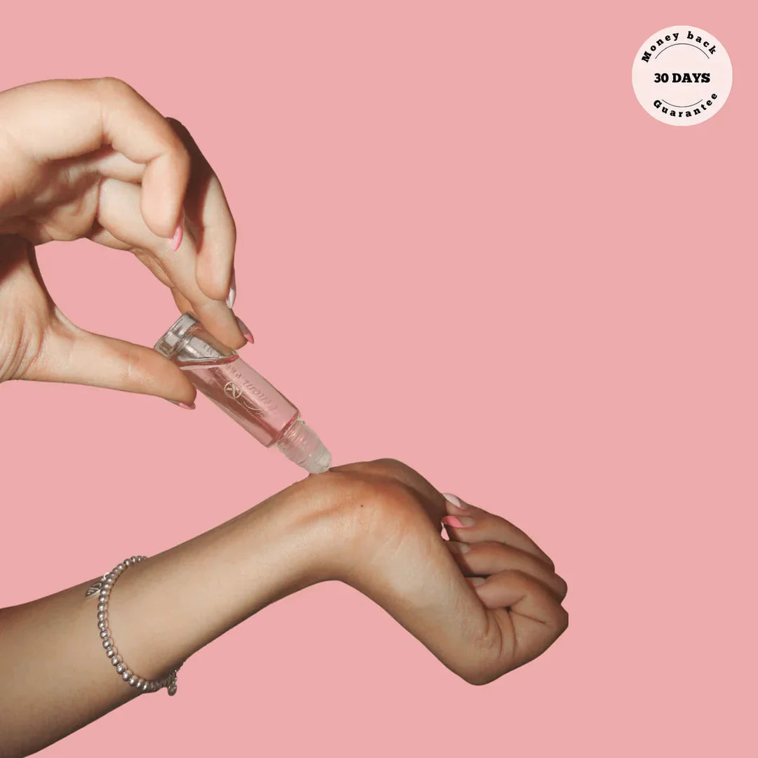 Pink perfume roller bottle held in hand, silver cap visible