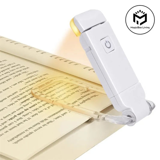 White clip-on LED book light with clear clamp, placed on an open book