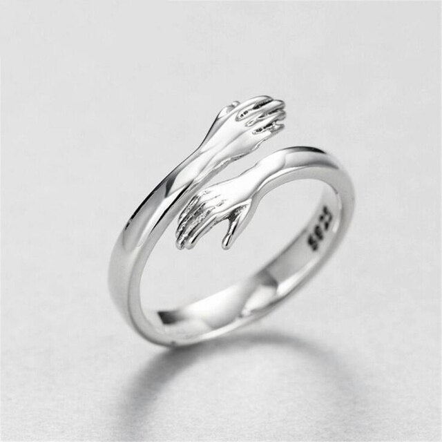 Silver-tone ring with raised hand design and open-heart cutout, side view