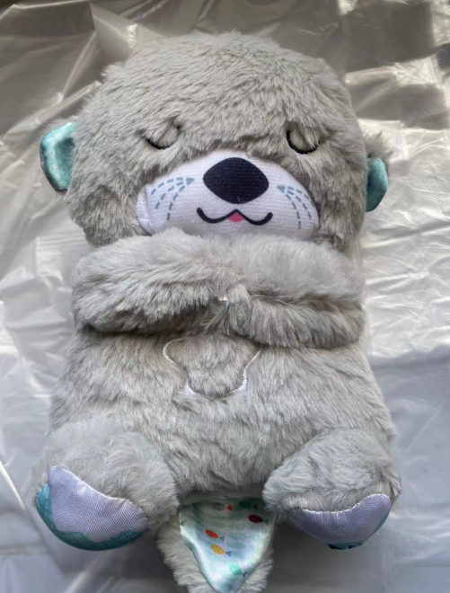 Grey sloth plush music toy with closed eyes and glowing snout area