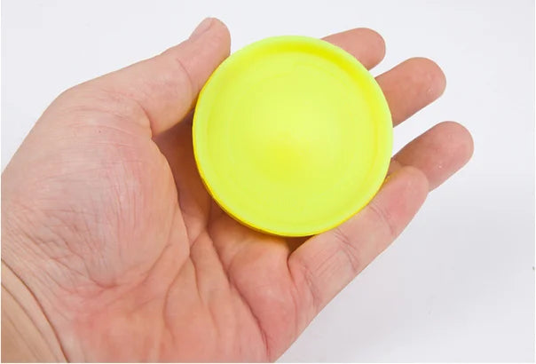 Neon yellow mini flying disc in hand, round top view with smooth surface.