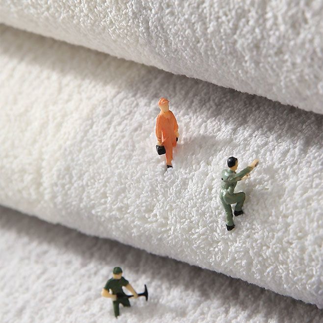 White plush bedroom mat close-up with small character appliques on textured surface