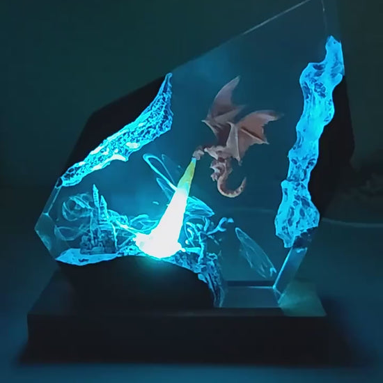 Glowing blue dragon etched in glass on a dark base, illuminated against a dim background.