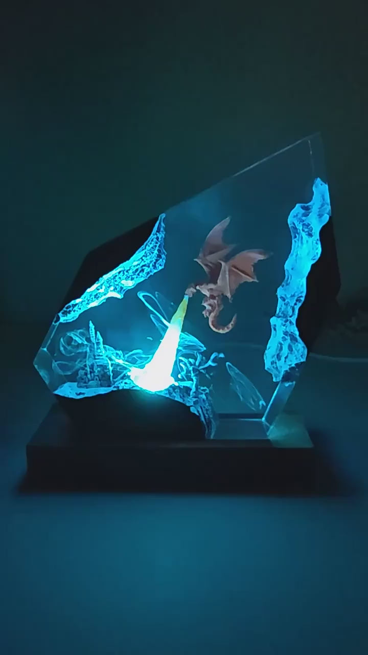 Glowing blue dragon etched in glass on a dark base, illuminated against a dim background.