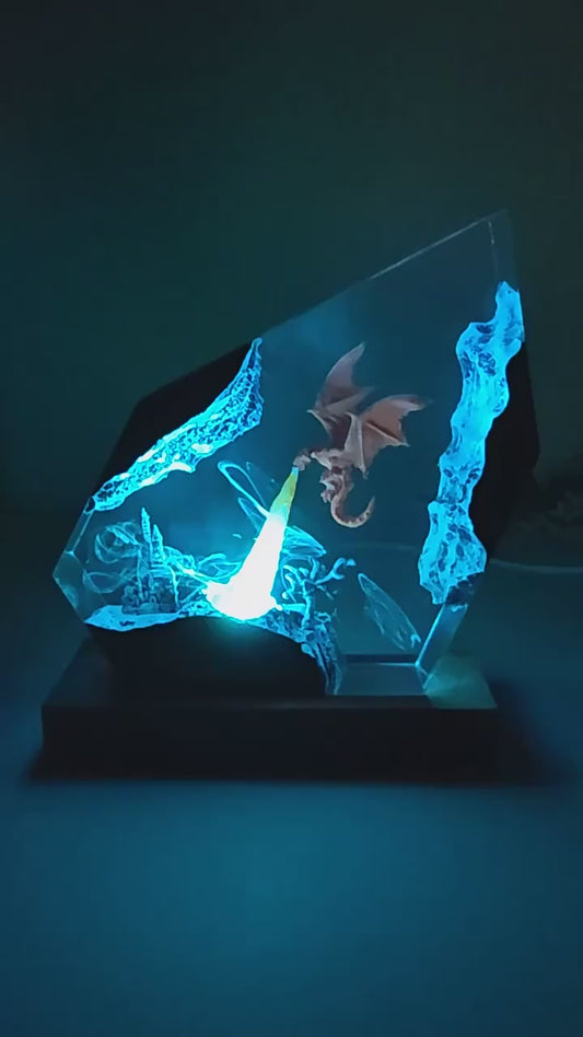 Glowing blue dragon etched in glass on a dark base, illuminated against a dim background.